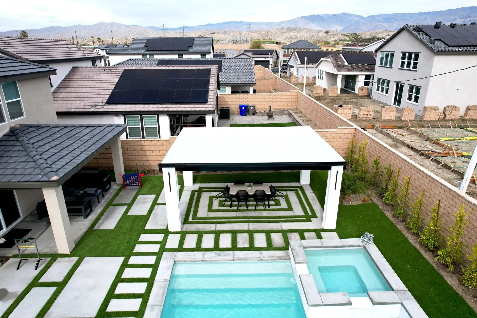 Aerial of a pool, spa and paver patio with a pergola