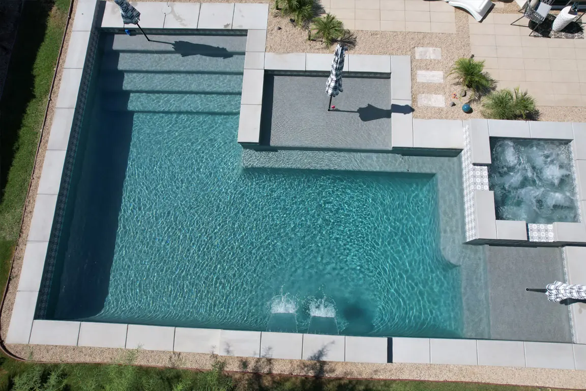 Vista aérea de una piscina geométrica con spa y repisa solar