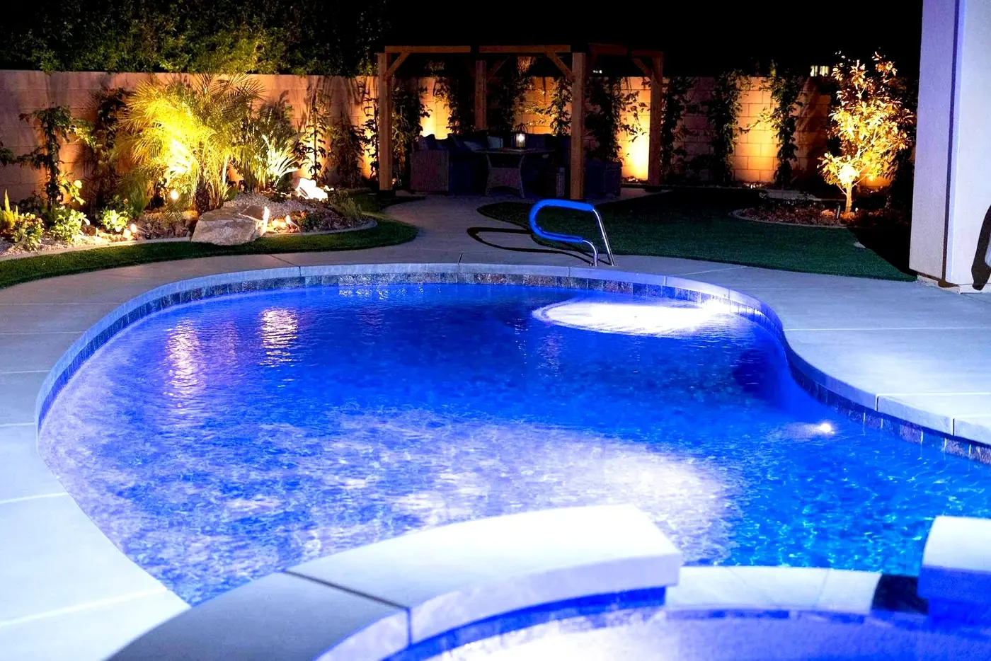 Freeform pool with blue LED lighting and uplit landscape