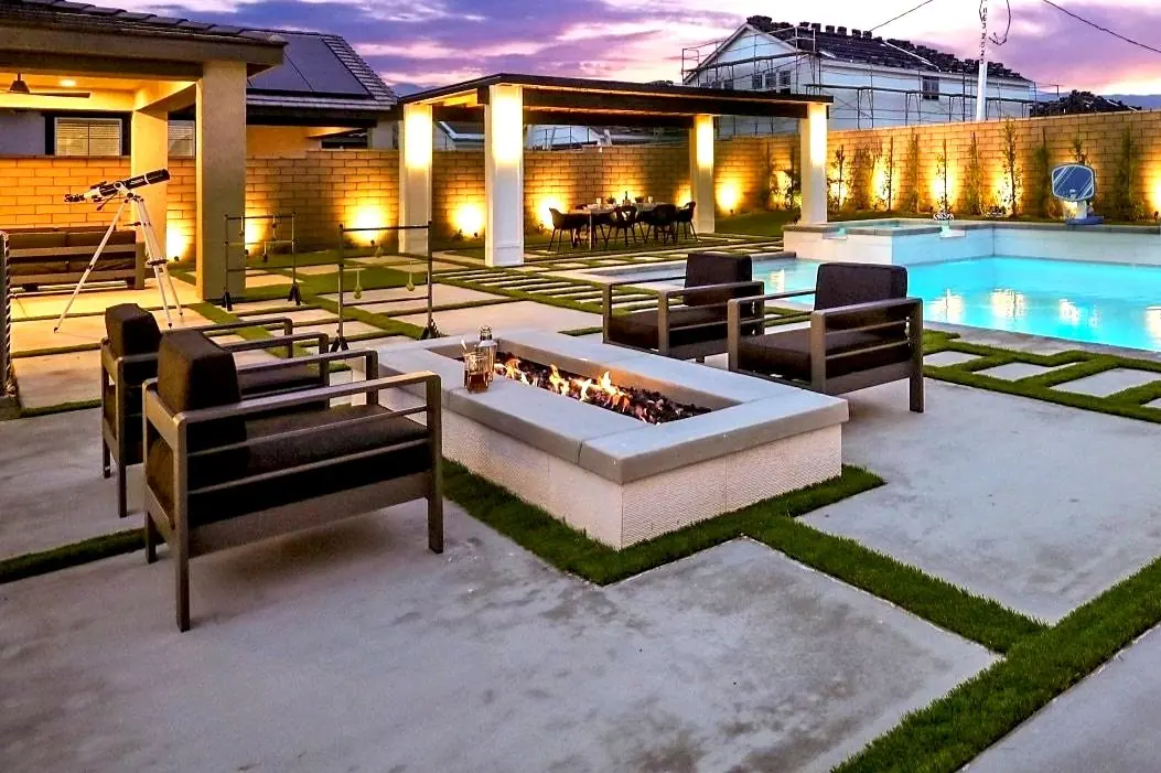 Outdoor living area with fire table and pool at night