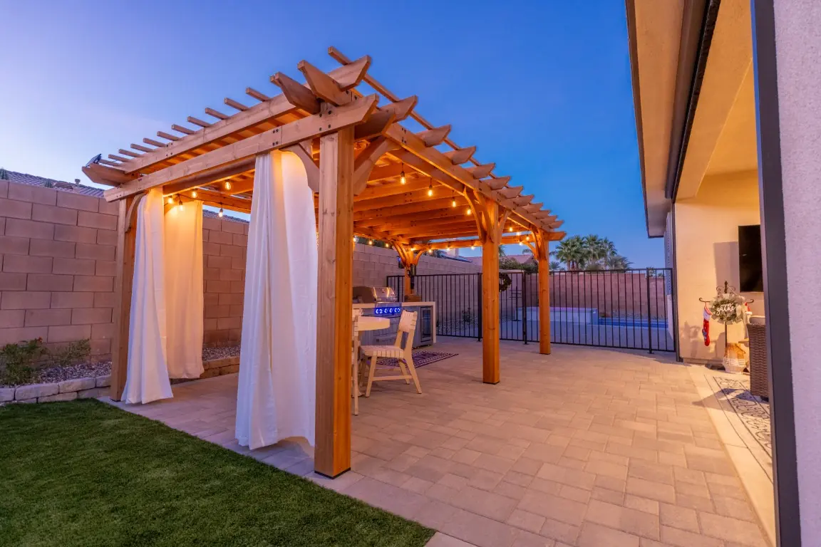 Wood pergola with curtains and lit patio at dusk