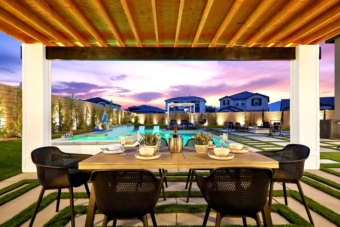 Covered patio dining area overlooking a pool at sunset