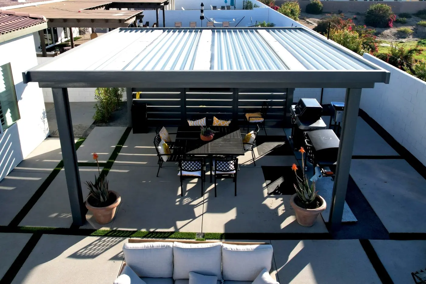 Steel pergola over an outdoor dining and lounge area