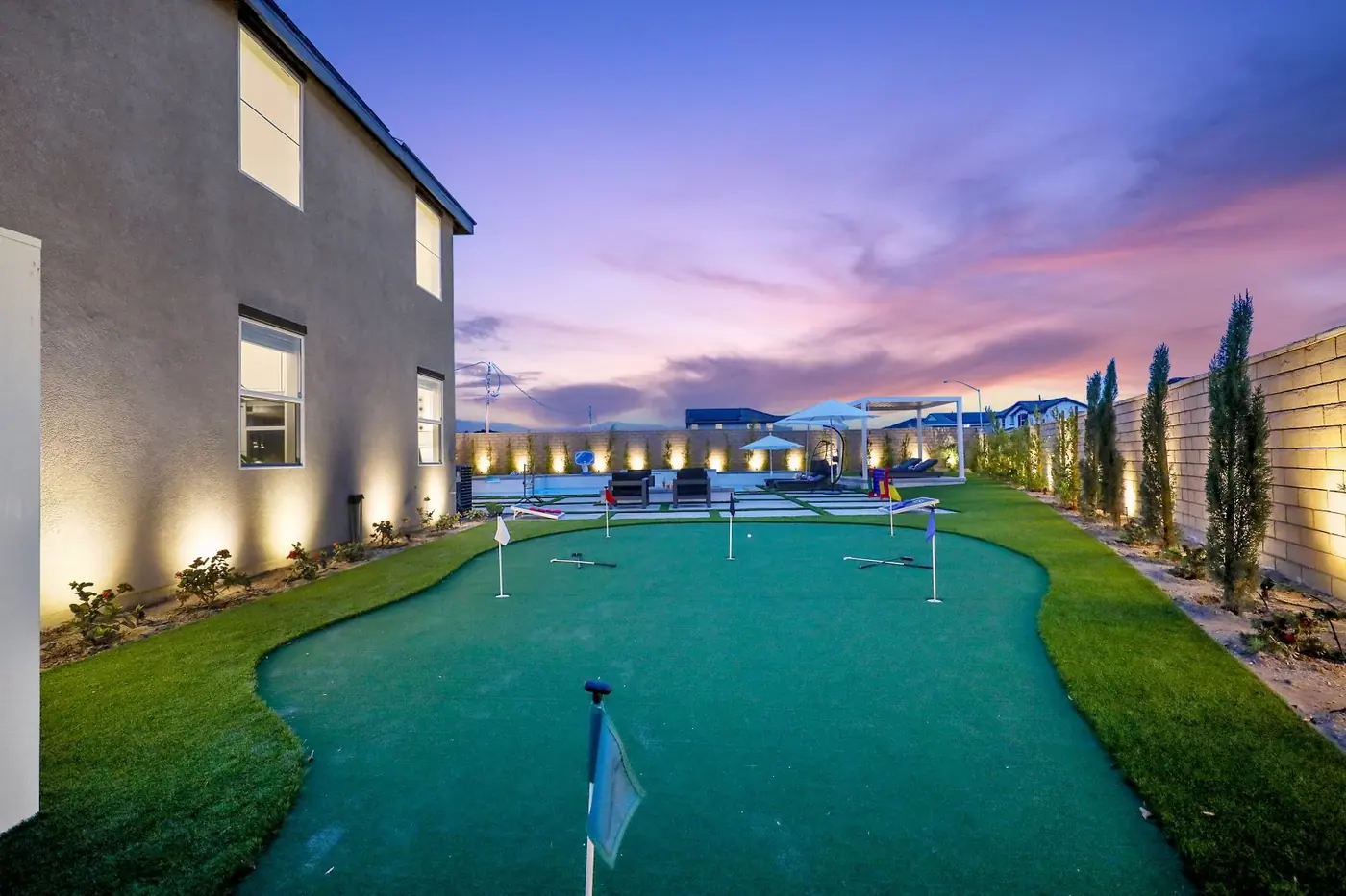 Backyard putting green at dusk with string lights