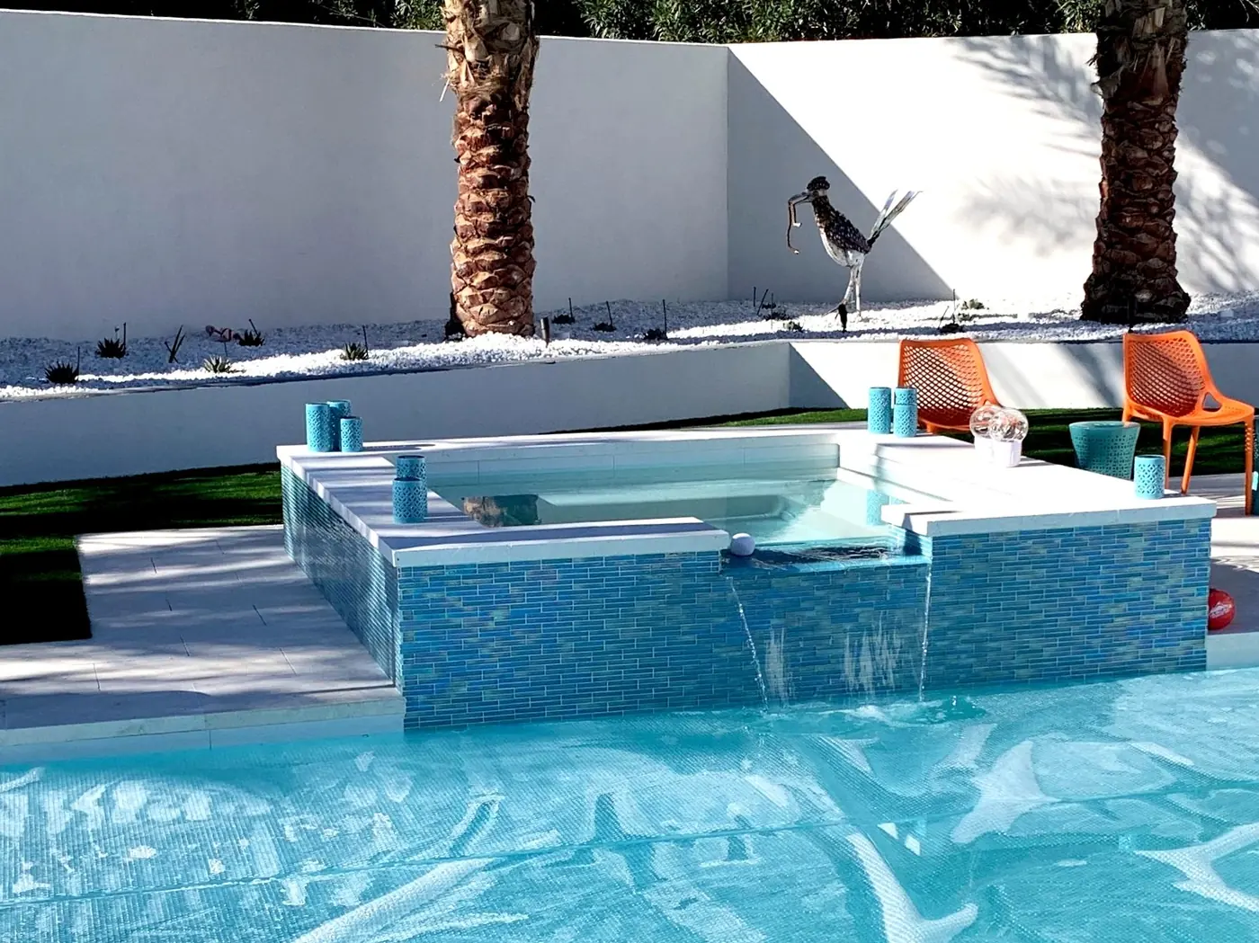 Raised mosaic spa spilling into the pool