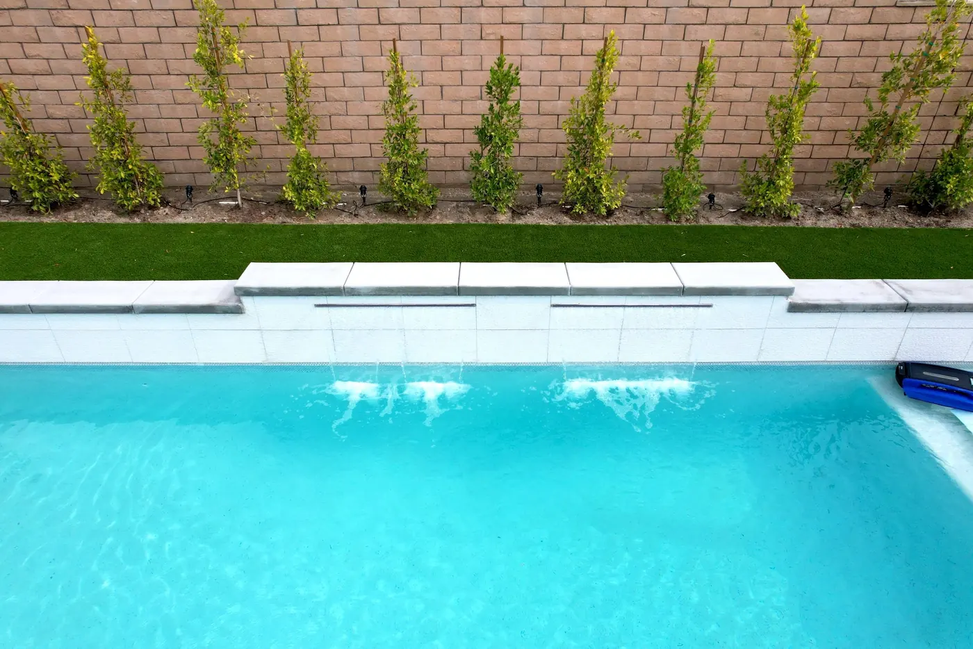 Bright turquoise pool with a sheer-descent water feature