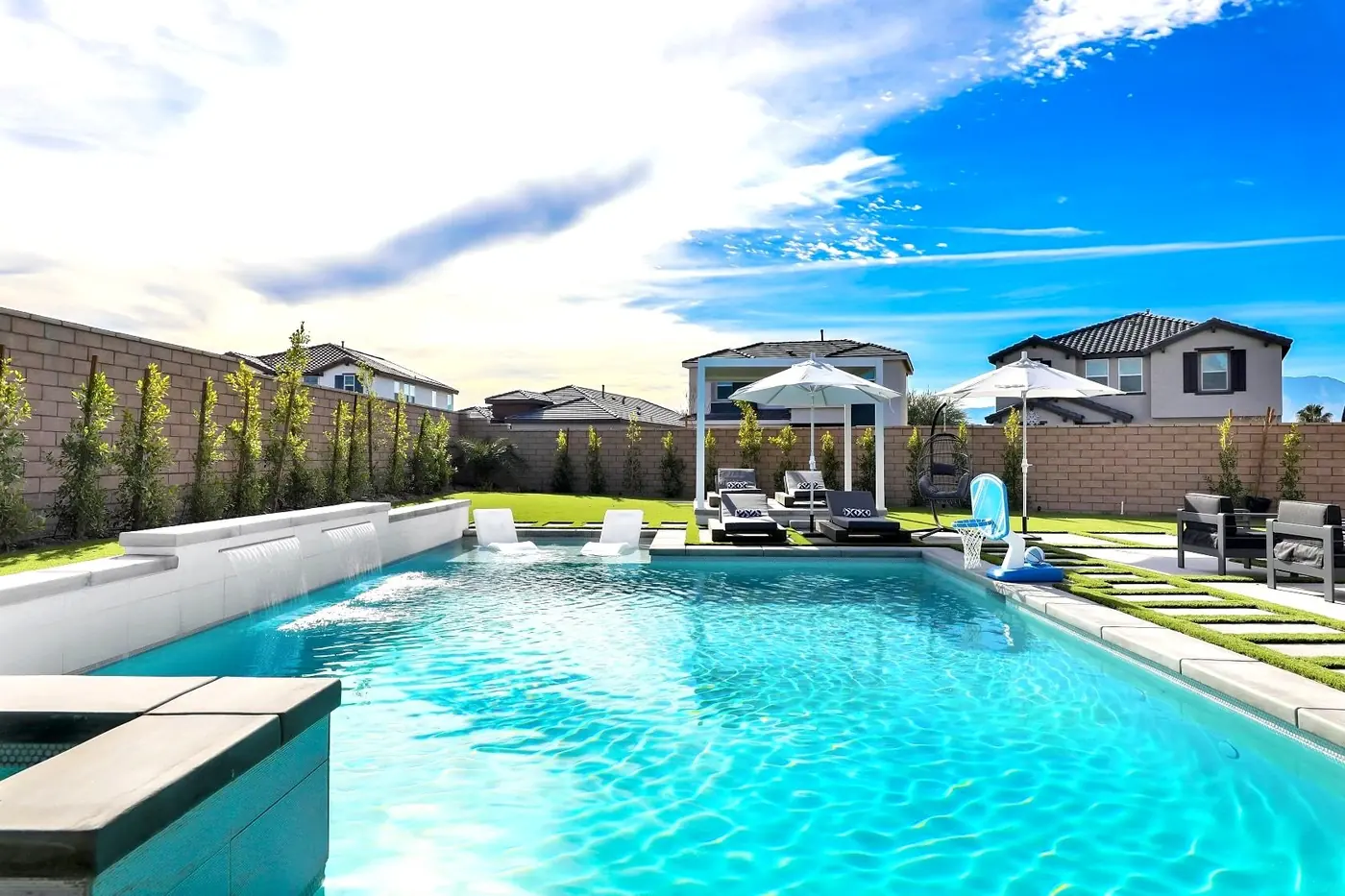 Turquoise pool with umbrellas and loungers in a desert backyard